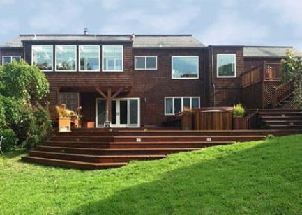 A backyard deck with stairs leading down to a grassy area.