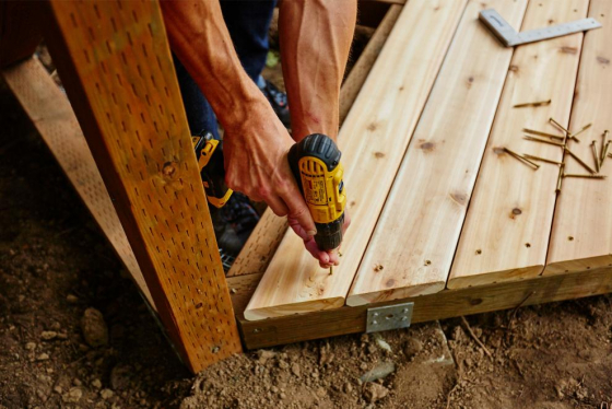 A man drilling as he works on building a new deck.