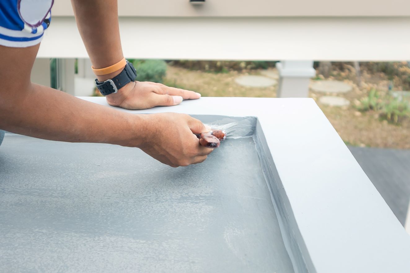 Man applying a protective coat to an outdoor service to help waterproof it.
